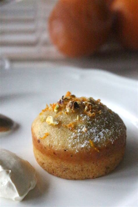 a small pastry on a white plate with oranges in the backgroung