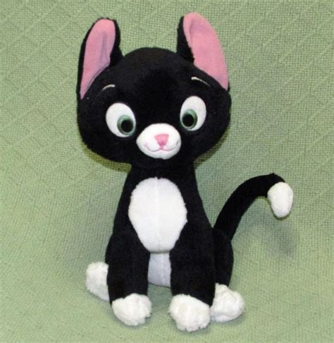 a black and white cat stuffed animal sitting on top of a green surface ...