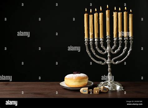 Silver menorah near sufganiyah and dreidels with symbols Nun, He, Pe ...