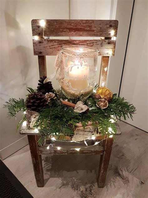 a wooden chair decorated with pine cones and greenery is lit up by ...