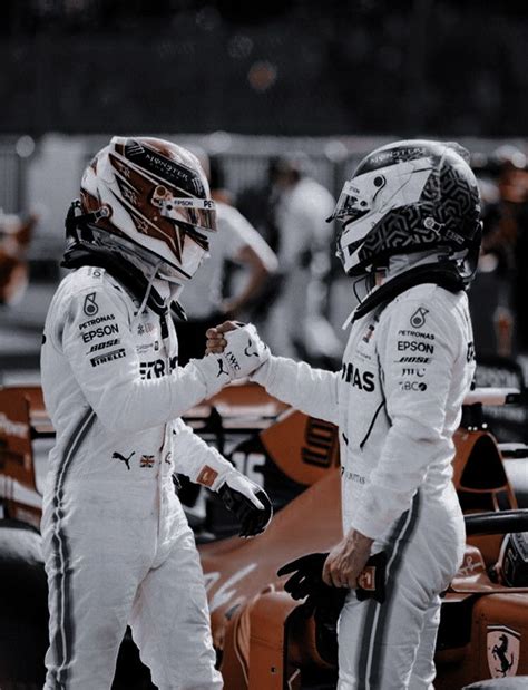 two racing drivers shaking hands next to each other