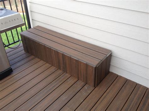 a wooden bench sitting on the side of a house next to a grill and ...