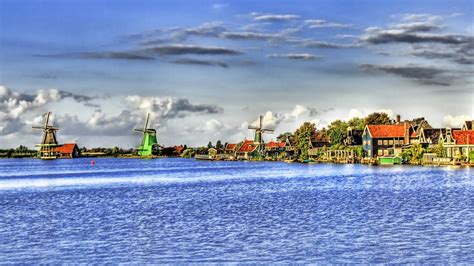 Blue body of water near three windmills and village houses under blue ...