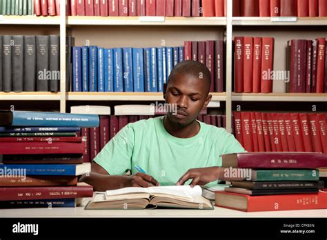 Male student studying with lots of books Stock Photo - Alamy