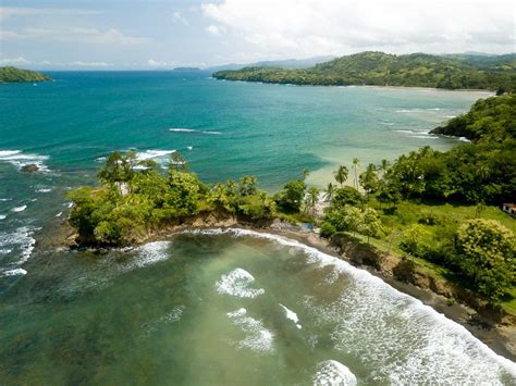 an aerial view of the ocean and beach with waves crashing on it's shore