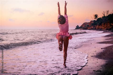 Silhouette of a girl in a pink dress on the beach, on the background of ...