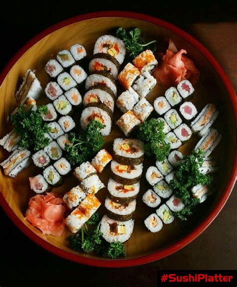 sushi platter with various types of sushi and vegetables on it in a red ...