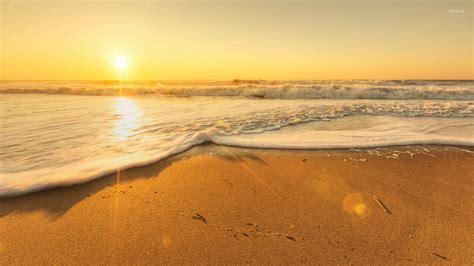 Golden sunset light reflecting on the waves reaching to the sand ...