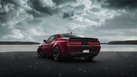 the rear end of a red sports car parked in front of a body of water