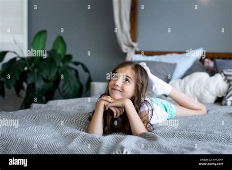 Beautiful little girl lying on bed at house. Portrait of a beautiful ...