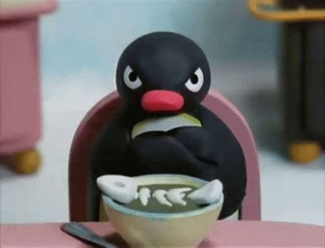 a toy penguin sitting at a table eating food