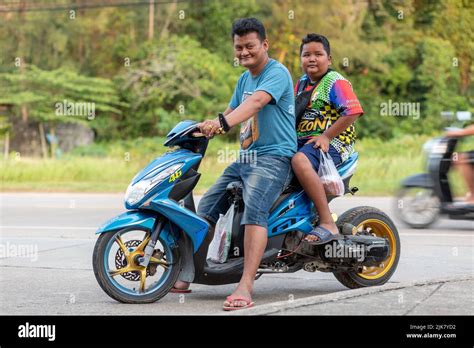 A Thai father and son, sat on a modified, custom motor scooter with ...