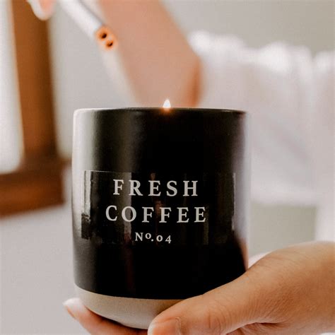 a woman holding a coffee mug with a lit candle in her hand and the ...