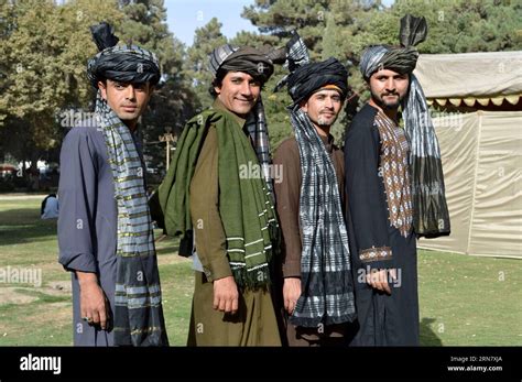 People in traditional Pashtun dresses pose for photos during a ceremony ...