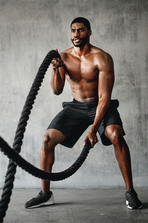 Muscular man working out on the battle ropes in a gym | premium image ...