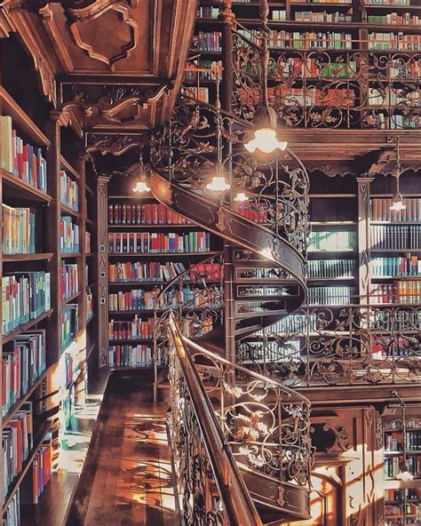 a spiral staircase in a library with bookshelves and chandeliers on ...