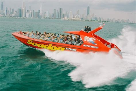 a red speed boat with people riding on it in the water near a city skyline