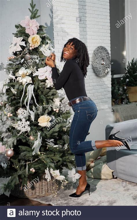 smiling black girl with curly hair decorates Christmas tree with ...