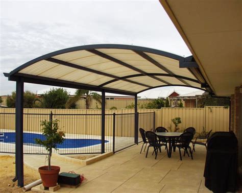 a patio covered in shade next to a swimming pool and fenced in area ...