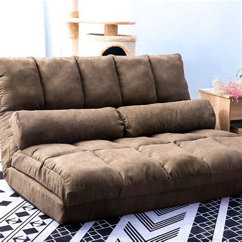 a brown futon couch sitting on top of a black and white rug