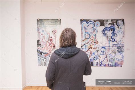 Rear view of Creative male artist watching his art piece in an art ...