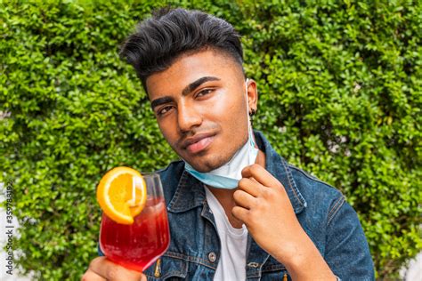 male portrait of young adult drinking colored cocktail at outdoor bar ...