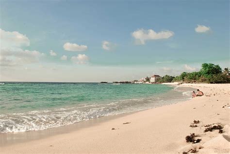 people are sitting on the beach near the water and in the sand by the ocean