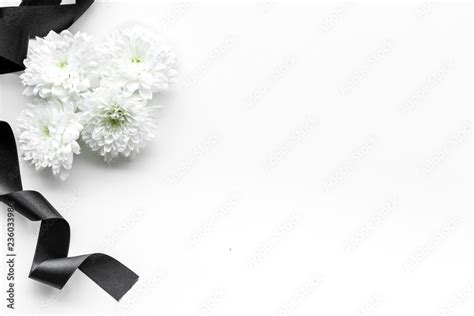 Funeral symbols. White flower near black ribbon on white background top ...