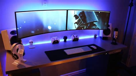 two computer monitors sitting on top of a desk with headphones and ...