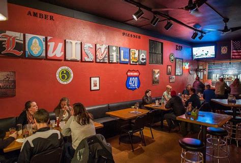 people sitting at tables in a restaurant with red walls and pictures on ...