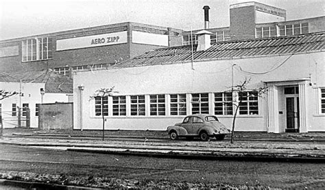 an old black and white photo of a car parked in front of a building ...