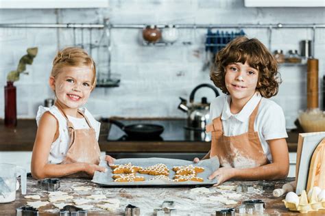 Cute happy kids in aprons holding baking tray with ginger cookies and ...