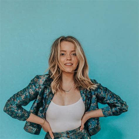 a woman standing in front of a blue wall with her hands on her hips and ...