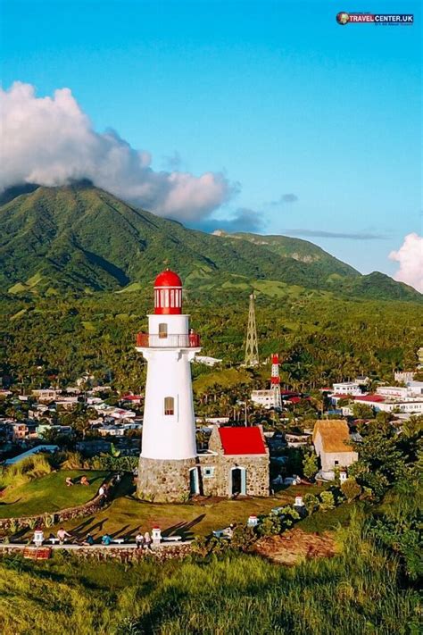 a white and red lighthouse surrounded by green hills