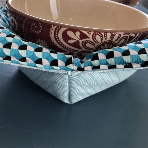 a blue and white bowl with a bow tie on it sitting on a table next to ...