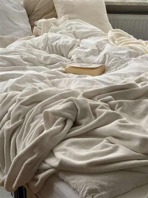 an unmade bed with white sheets and pillows