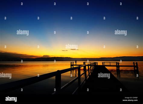 A woman on a jetty in Lake Illawarra watching the sunset Stock Photo ...