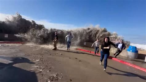 Terrifying moment rogue wave slams past seawall and hits fleeing beachgoers