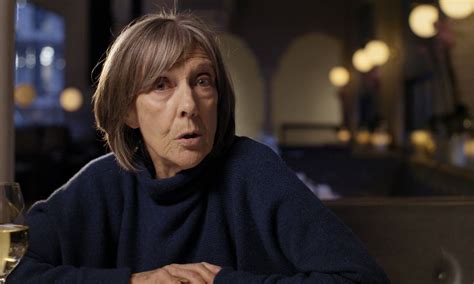 an older woman sitting at a table with a glass of wine