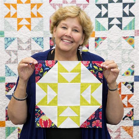 a woman holding up a piece of quilt