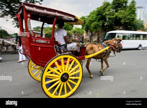 A passing two-wheeled horse-drawn carriage (kalesa) in Manila ...