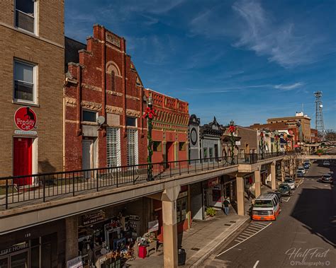 a city street lined with tall brick buildings and shops under a blue ...