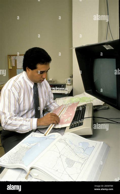 Austin Texas USA: Hispanic cartographer looks over maps in his office ...