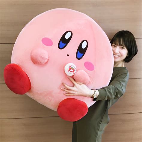 a woman holding a large pink stuffed animal with eyes and nose on it's back