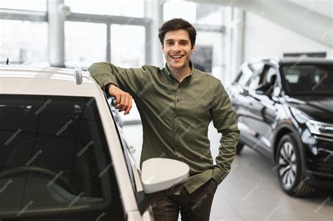 Premium Photo | Handsome young guy posing near his new car smiling at ...