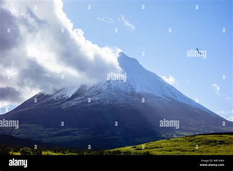 Mount Pico volcano under blue sky with cloud coming off summit and bird ...