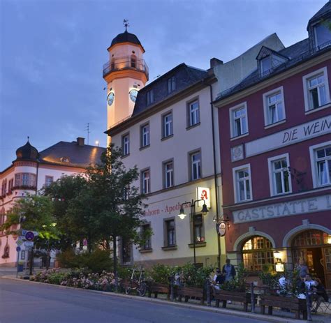 a clock tower in the middle of several buildings at dusk, with people ...