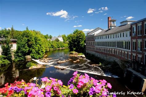 a river running through a lush green forest next to tall buildings and ...