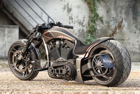 a motorcycle parked on the side of a road next to a cement wall with ...