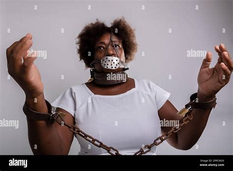 Portrait of a black woman in chains with an iron mask over her mouth ...